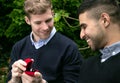 Engagement proposal betwen two gay men as one man proposes with an engagement ring in red box Royalty Free Stock Photo