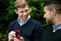 Engagement proposal betwen two gay men as one man proposes with an engagement ring in red box Royalty Free Stock Photo