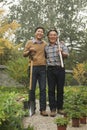 Two generation working in garden, smiling and holding gardening tools Royalty Free Stock Photo