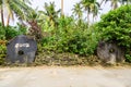 Two giant prehistoric megalithic stone coins or money rai, one signed 2012, by the muddy wet dirt road under palm trees. Yap.