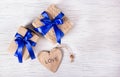 Two gift boxes with blue ribbons and a heart from a tree on a white wooden background. Valentine`s day. Copy space. Royalty Free Stock Photo