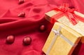 Two gift boxes with bows, on red wavy satin fabric with Christmas balls. Royalty Free Stock Photo