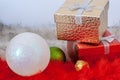 Two gift boxes and two Christmas balls on red and white fur. Royalty Free Stock Photo