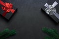 Two gift boxes with red and silver ribbons on a black surface. Christmas tree branch. Place for an inscription Royalty Free Stock Photo