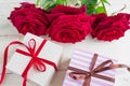 Two gift boxes with ribbon bow and bautiful red roses on wooden background. Greeting card for holiday Royalty Free Stock Photo