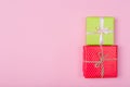 Two gift boxes wrapped in color green and red polka dots paper and tied with pink and craft ribbon on pink background