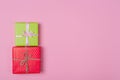 Two gift boxes wrapped in color green and red polka dots paper and tied with pink and craft ribbon on pink background