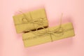 Two gift boxes wrapped of craft paper and burlap ribbon on the pink background, top view, close-up Royalty Free Stock Photo