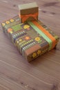 Two Gifts In Vintage Wrapping Paper With Flowers And Mushrooms, Green Brown And Orange, Neutral Wood Background