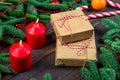 Two gifts wrapped in craft paper next to red burning candles Royalty Free Stock Photo