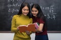 Two gilrs are cheerful beautiful reading a book on the board background, Education Concept.