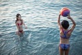 two gils in swimsuits standing in the water and playing with colourful ball in the sea Royalty Free Stock Photo