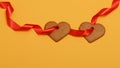 Two gingerbread hearts strung on a red ribbon