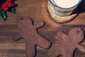 Two gingerbread man cookies with a glass of milk on a wooden backgroun, close up. Holiday concept, macro photography Royalty Free Stock Photo