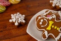 Two gingerbread men with colorful icing on a white dessert plate on a wooden table with gingerbread and caramels in the background
