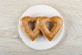 Two gingerbreads in shape of heart in plate on wooden table. Top view