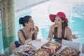 Two Girl eating pizza best relax in the hotel pool