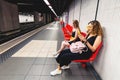 girl friends reading smartphon in metro while waiting for the train. Social media and internet addiction concept