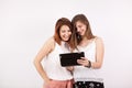 Two girl friends smiling and looking at a tablet PC Royalty Free Stock Photo