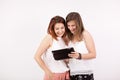 Two girl friends smiling and looking at a tablet PC Royalty Free Stock Photo