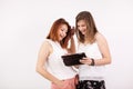 Two girl friends smiling and looking at a tablet PC Royalty Free Stock Photo