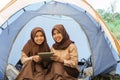 two girl scouts in veil smiling using tablet in tent