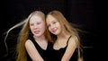 Two girl teenager posing on black background in studio and hair moving on wind Royalty Free Stock Photo