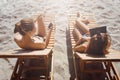 Two girlfriends having fun with VR glasses and smartphone on beach