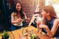 Two girlfriends having healthy lunch in cafe. Young woman taking picture of food with smartphone posting on social media Royalty Free Stock Photo