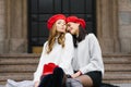 Two girlfriends in red berets sit on the steps, smiling and blowing a kiss. Happiness and joy