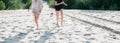 Two girlfriends run with a small dog along the sand on the beach in summer Royalty Free Stock Photo