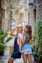 Two girlfriends on strret making funny face expressions, having fun together. Young women walking on street of European city. Royalty Free Stock Photo