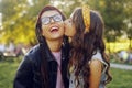 Two girlfriends are walking in the park. Sisters gossip. The girl kisses her friend on the cheek. Two beautiful brunettes at
