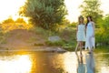 Two girlfriends, young girls in white dresses and flower wreaths on their heads, standing in a river of water, near the shore, Royalty Free Stock Photo