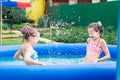 Two girls with afro-braids have fun splashing water in an inflatable pool on a summer day in the backyard Royalty Free Stock Photo