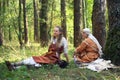 Two girls in the ancient Russian clothes sitting on the grass during the festival of historical reconstruction