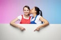 Two girls in aprons pose with a white Billboard. advertising concept