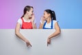 Two girls in aprons pose with a white Billboard. advertising concept