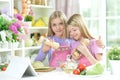 Two girls in aprons preparing fresh salad