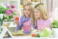 Two girls in aprons preparing fresh salad