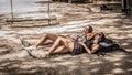 Two girls backpackers lying on ranches on tropical beach sand in shade Royalty Free Stock Photo