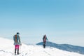 two girls with backpacks walk along a path in the winter mountains. hiking in the mountains Royalty Free Stock Photo