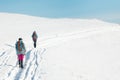 two girls with backpacks walk along a path in the winter mountains. hiking in the mountains Royalty Free Stock Photo