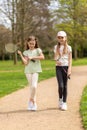 Two girls with badminton rackets on a park path.