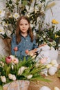 Two girls in a beautiful Easter photo zone with flowers, eggs, chickens and Easter bunnies. Happy Easter holiday. Royalty Free Stock Photo