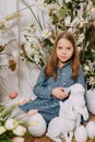 Two girls in a beautiful Easter photo zone with flowers, eggs, chickens and Easter bunnies. Happy Easter holiday. Royalty Free Stock Photo