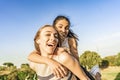 Two girls best friends having fun outdoor in a green nature park looking at camera laughing and joking. Young brunette woman Royalty Free Stock Photo