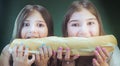 Two girls biting a big baguette