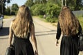 Two girls in black dresses walk down road. Girls return from funeral. Black clothes Royalty Free Stock Photo