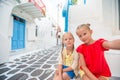 Two little girls taking selfie photo outdoors in greek village on narrow street in Mykonos Royalty Free Stock Photo